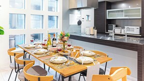 A modern dining area with a long table set for a meal, surrounded by chairs. - STARRY STAY HOUSE SHIBUYA I (Tokyo)