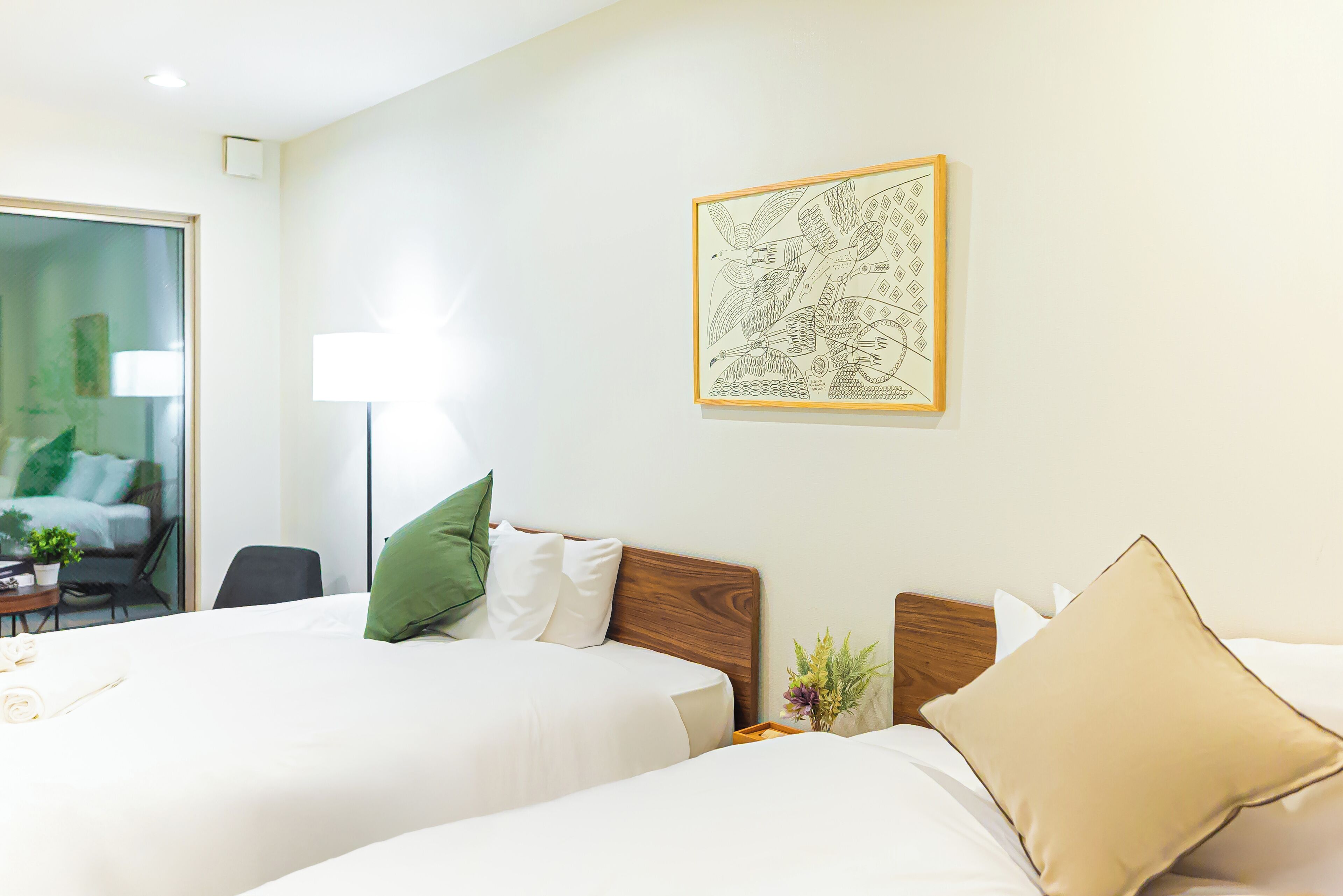A hotel room with two beds, a wooden headboard, a green pillow, a beige pillow, and a framed map on the wall.