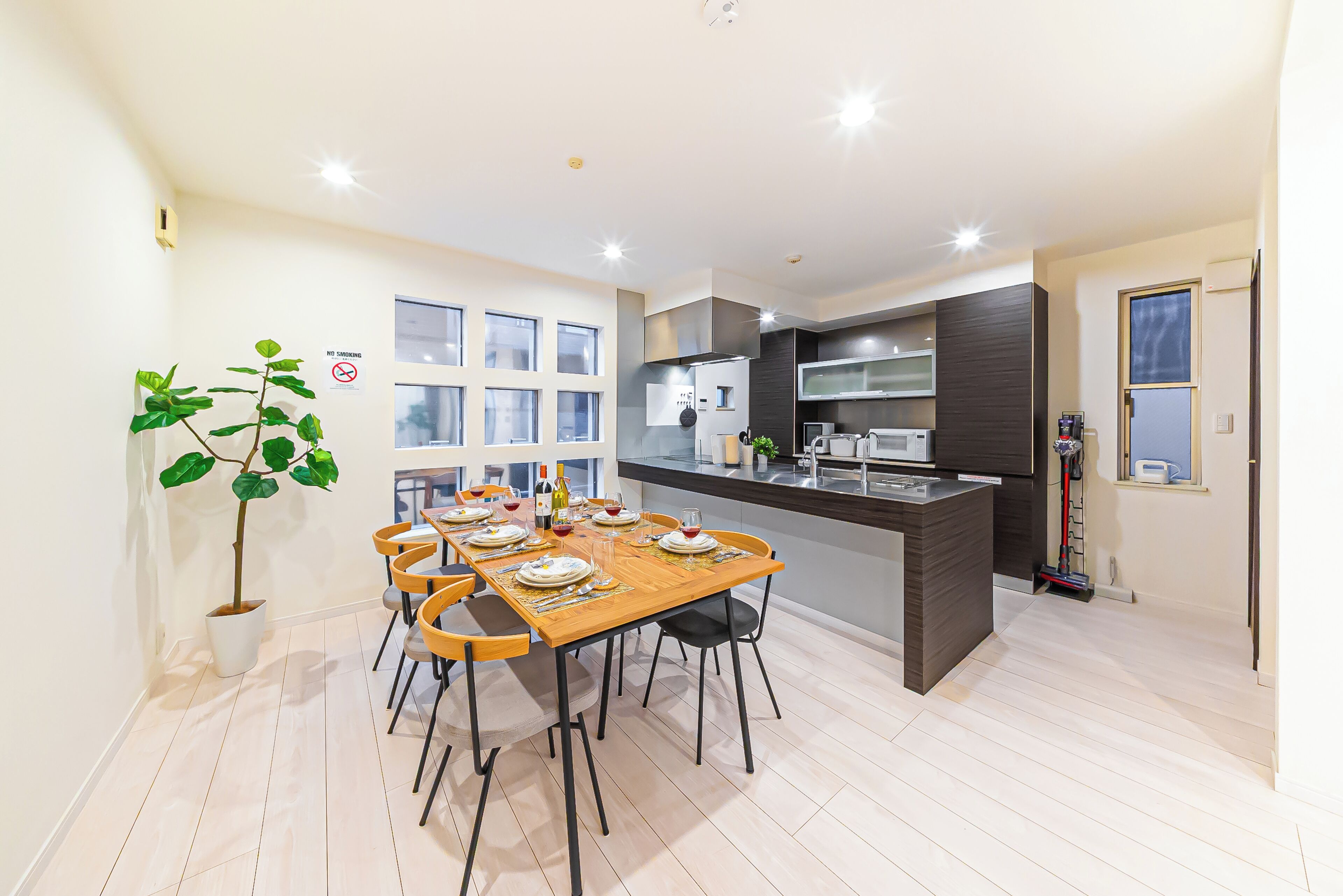 Una cucina moderna con zona pranzo, che include un tavolo in legno, sedie e un'isola con elettrodomestici.