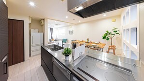 A modern kitchen with stainless steel appliances, a dining area with a wooden table and chairs, and a large window providing natural light. - STARRY STAY HOUSE SHIBUYA I (Tokyo)