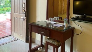 A room with a wooden desk, a mirror, a television, and a door leading outside. - The Grand Oak By TERASTAY (Virajpet)