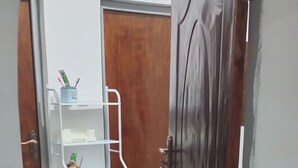 A hallway with a wooden door, a white shelf unit, and a patterned rug. - Lux Suites Siyoi Gardens Kitale (Kitale)