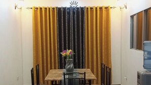A dining area with a table and chairs, a vase with flowers, and a water dispenser. - Lux Suites Siyoi Gardens Kitale (Kitale)