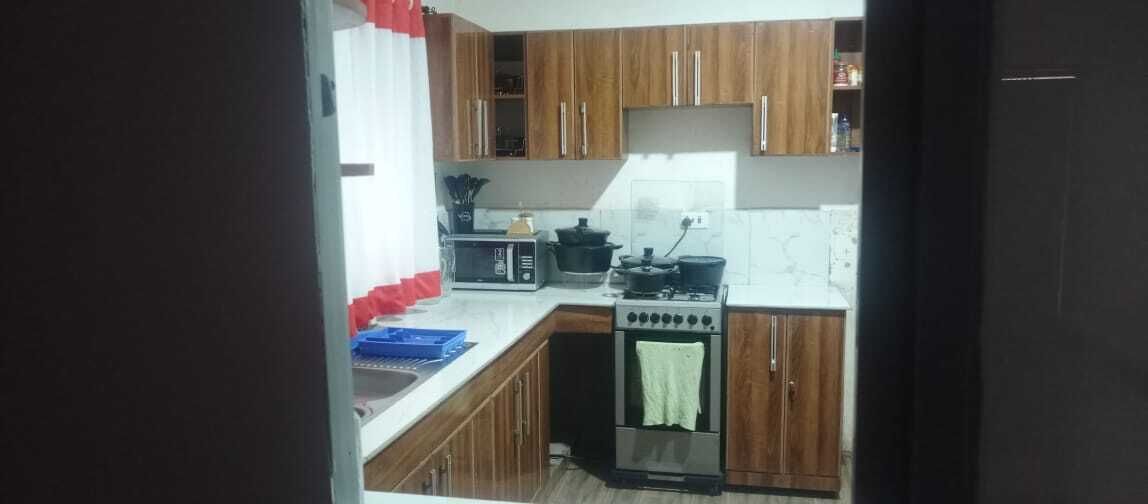 Una cocina con armarios de madera, estufa, microondas y lavaplatos.