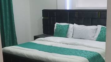A bedroom with a bed, a nightstand, a green curtain, and a white rug.