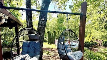 Dos sillones colgantes sujetos a una estructura de madera en un jardín.