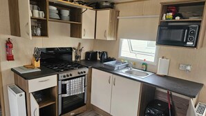 Una cocina compacta equipada con estufa, horno, fregadero y microondas.