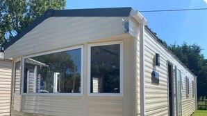 Una casa móvil con puerta principal, dos ventanas y un pequeño porche.