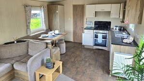Interior de una caravana compacta con kitchenette, comedor y zona de estar.