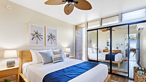 Ein geräumiges Schlafzimmer mit einem großen Bett, einem Deckenventilator und Blick durch eine Schiebetür auf einen Balkon.
