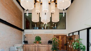 Un área de recepción con un mostrador de madera, plantas en macetas y lámparas colgantes.
