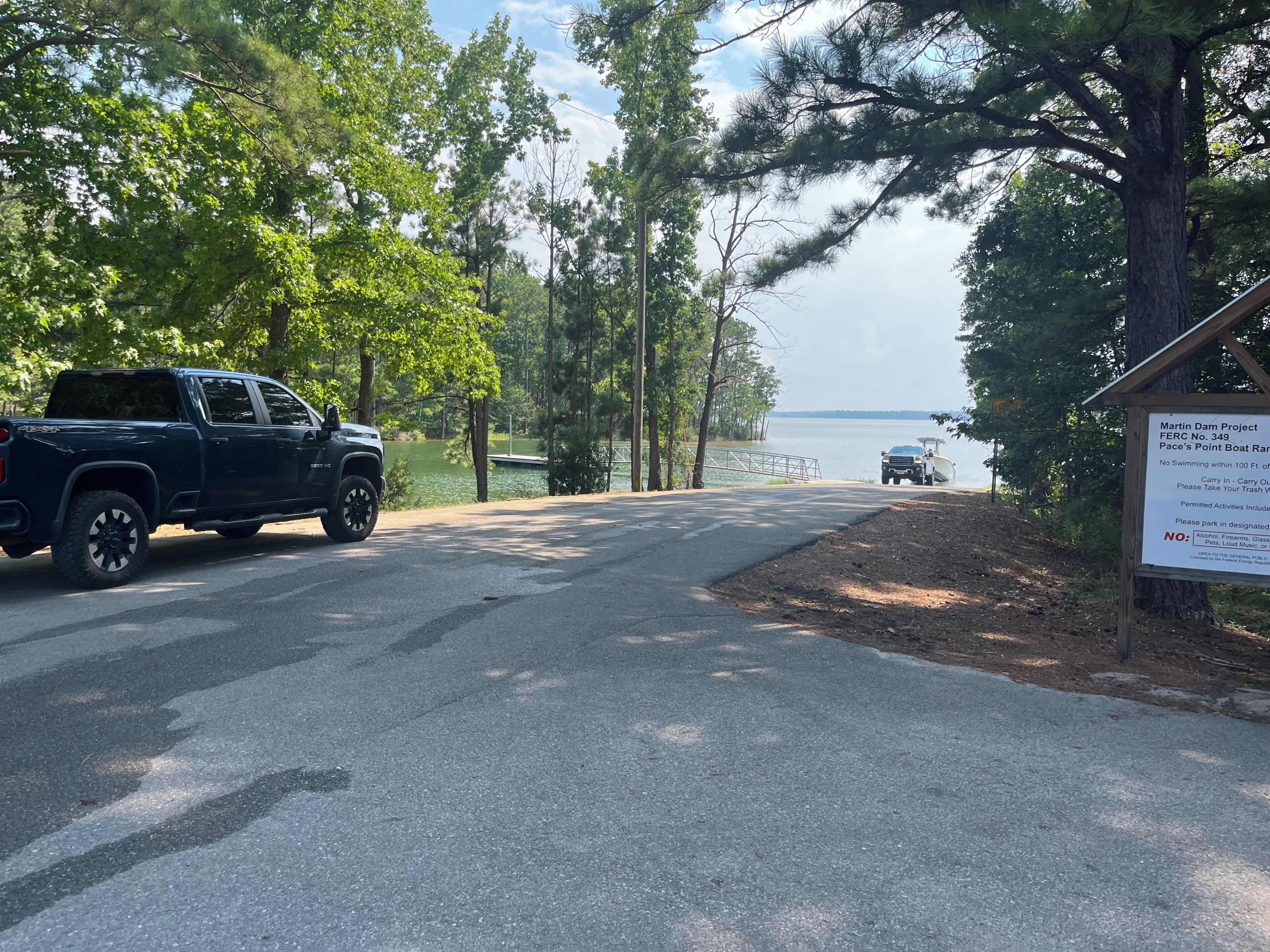 A paved road leading to a body of water with a truck parked on the side.