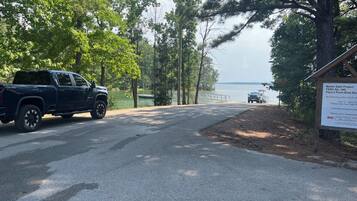 A paved road leading to a body of water with a truck parked on the side.