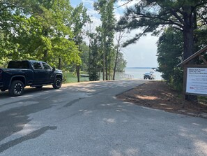 A paved road leading to a body of water with a truck parked on the side. - Rest-Relax-Reconnect-Renew in beautiful, serene, wooded, gated Lake Martin Cabin (Dadeville)