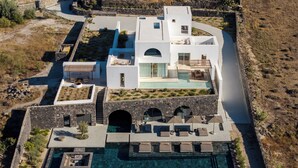 En moderne villa med swimmingpool, stenbuar og udendørs siddepladser.