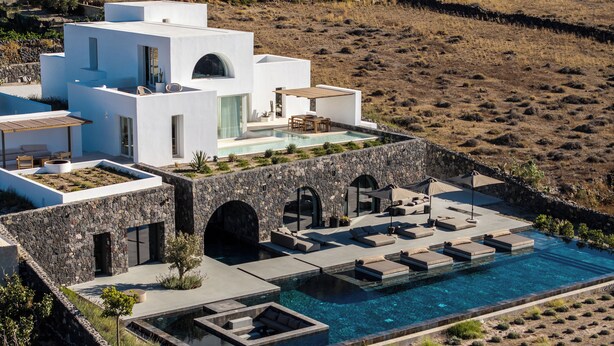 En moderne villa med swimmingpool, stenhvælv og udendørs siddeområder.