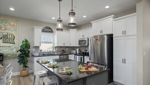 A modern kitchen with white cabinets, stainless steel appliances, and a central island with fresh produce.