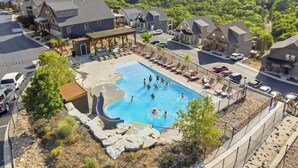 A residential area with a swimming pool surrounded by houses, a covered patio, and a view of a lake.