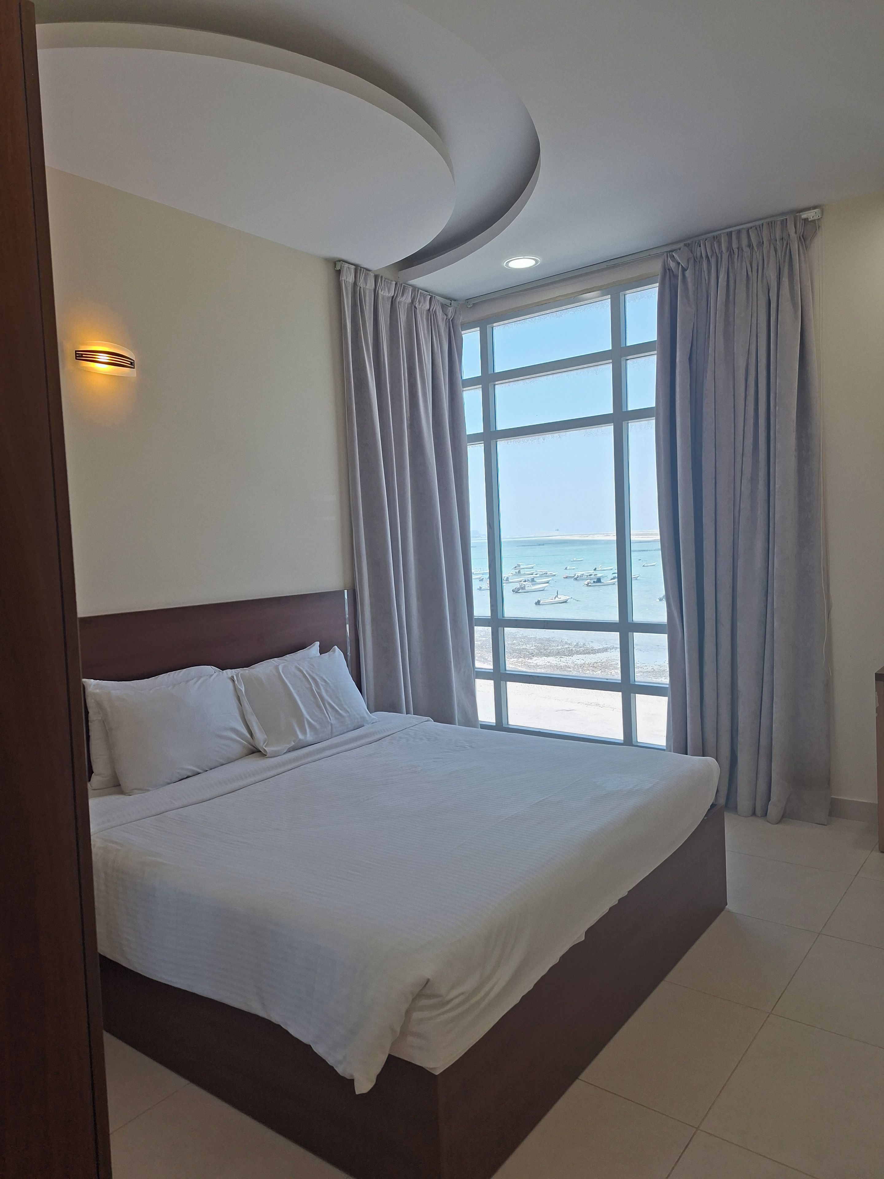 A hotel room with a large bed, a view of the beach, and a curved ceiling.