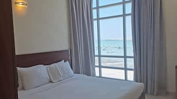 A hotel room with a large bed, a view of the beach, and a curved ceiling.
