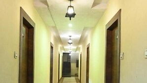 Un lungo e stretto corridoio con porte su entrambi i lati, un pavimento lucido e un lampadario.