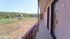 Un balcone con vista su un paesaggio rurale, che include campi e edifici in lontananza.