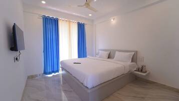 Une chambre d’hôtel moderne dotée d’un grand lit, d’un téléviseur à écran plat fixé au mur et d’un ventilateur de plafond.