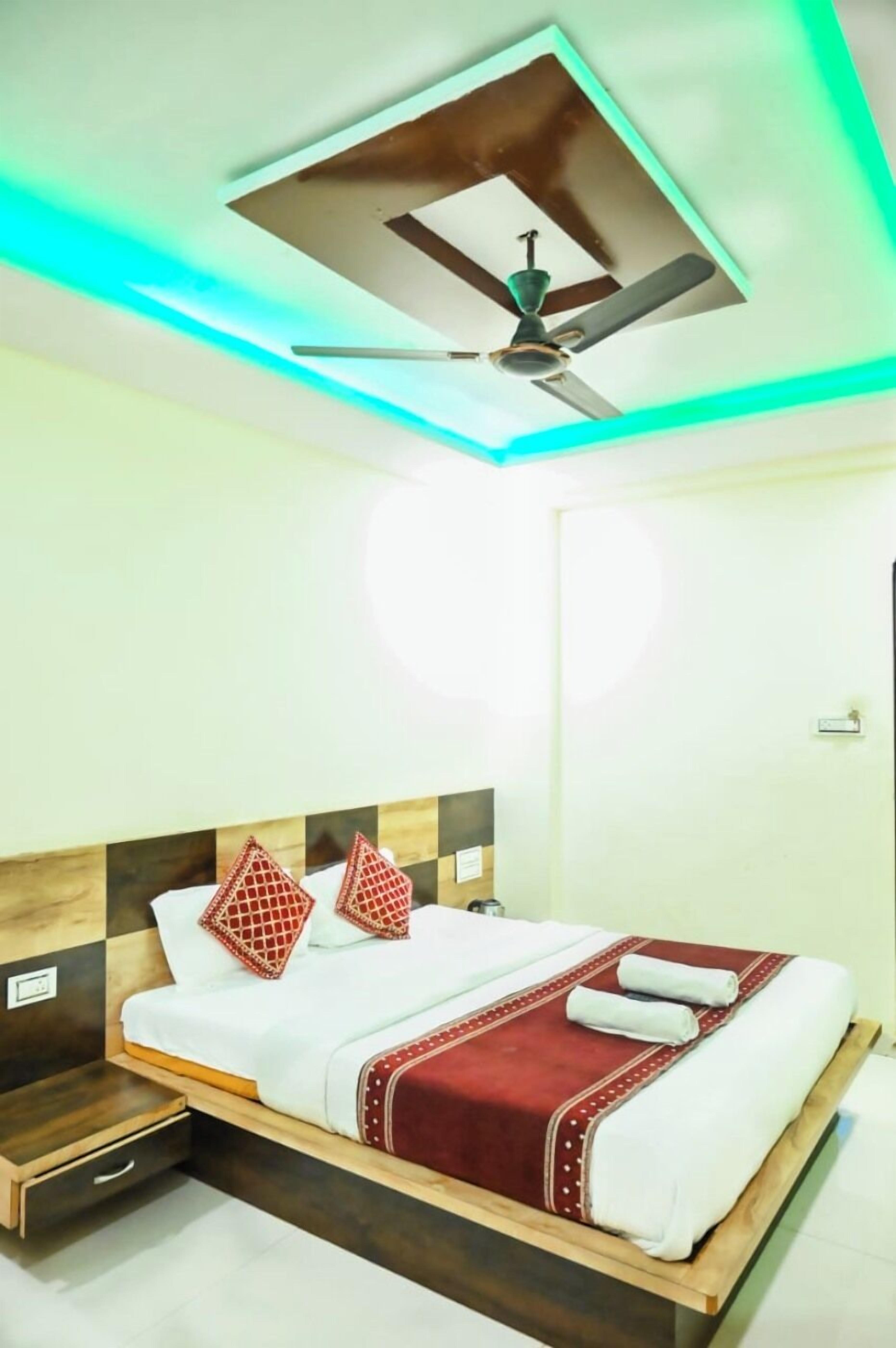 A hotel room with a bed, a ceiling fan, and a wooden headboard.