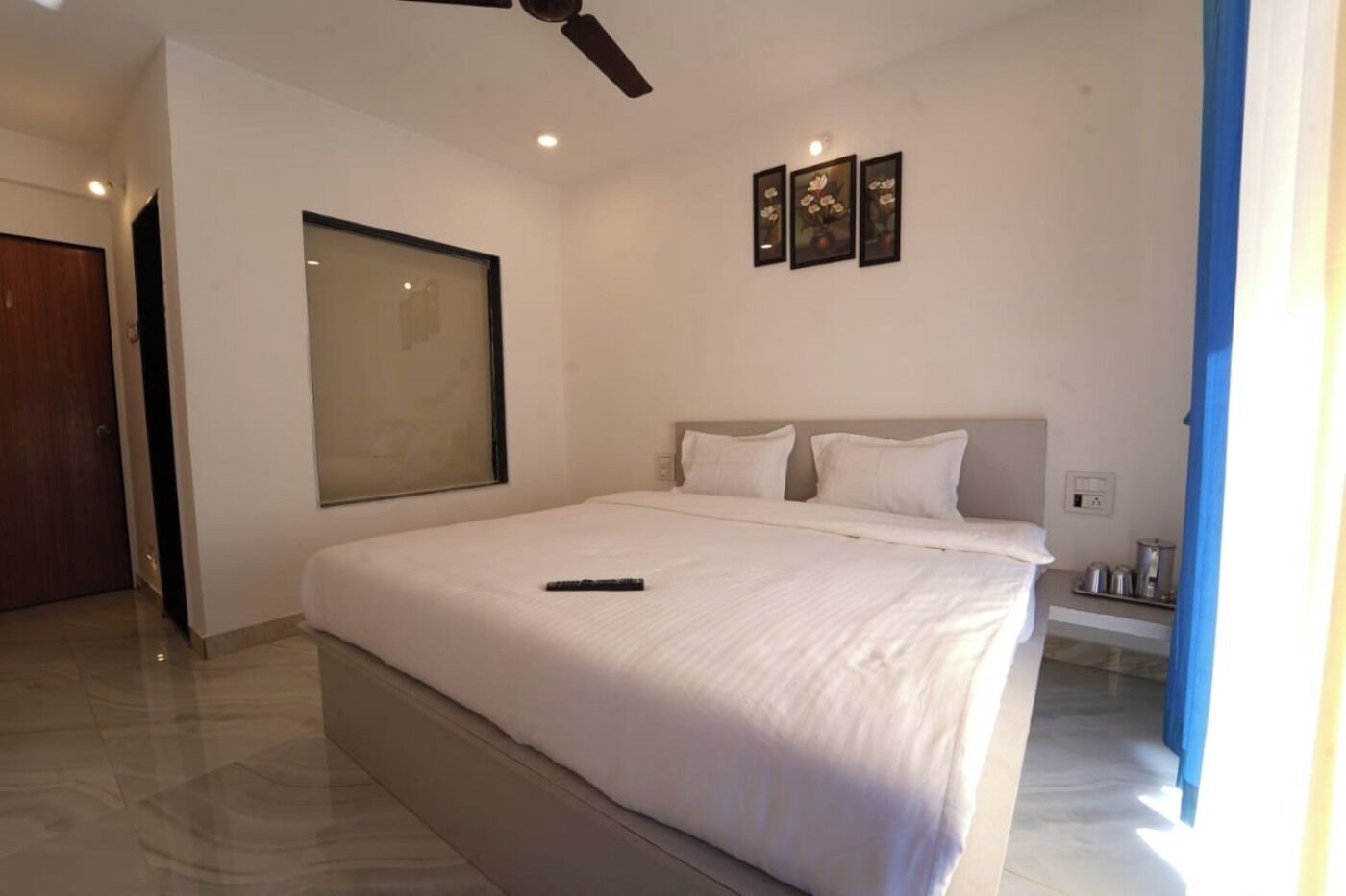 A modern bedroom with a large bed, a ceiling fan, and a window.