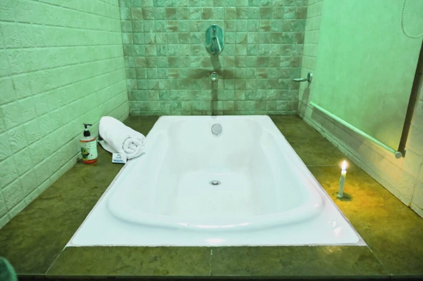 Une salle de bain avec une baignoire, une serviette et une bouteille de shampoing.