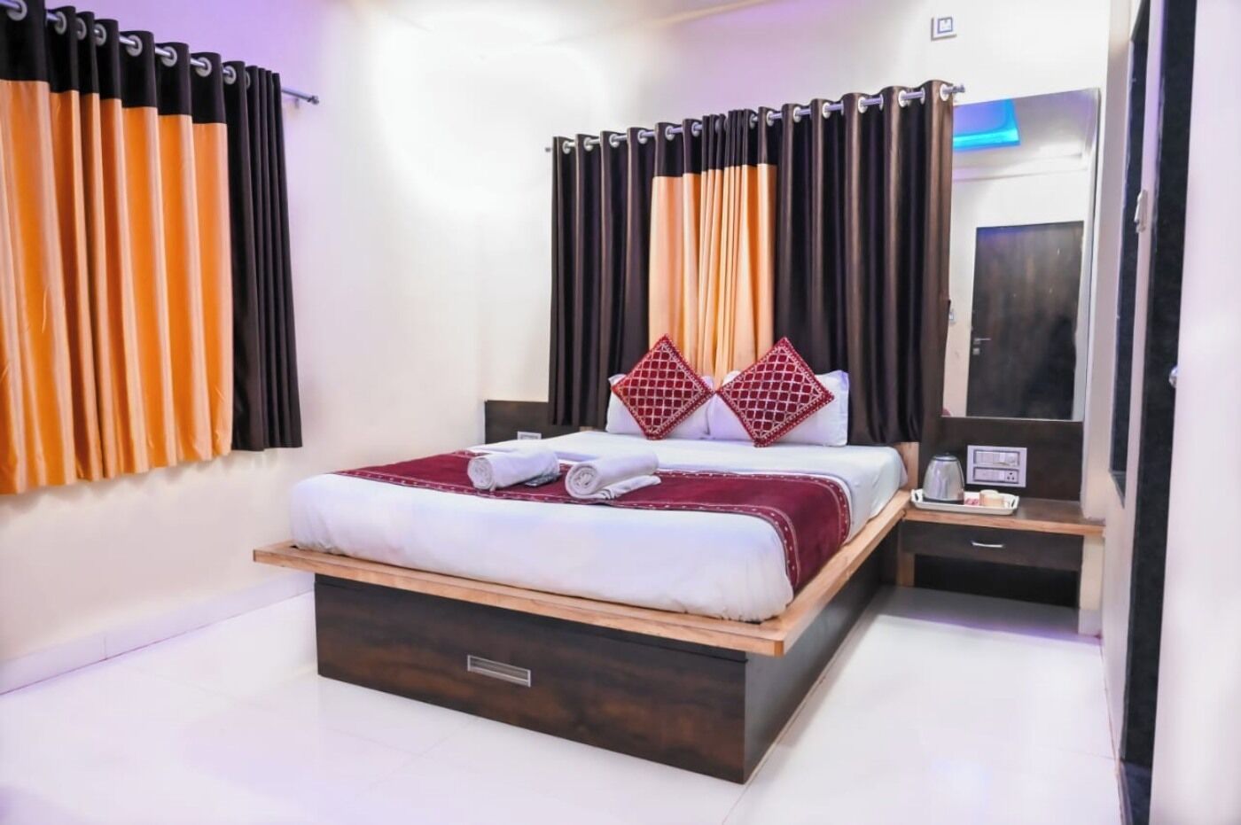 A modern hotel room with a large bed, a bedside table, and a mirror.
