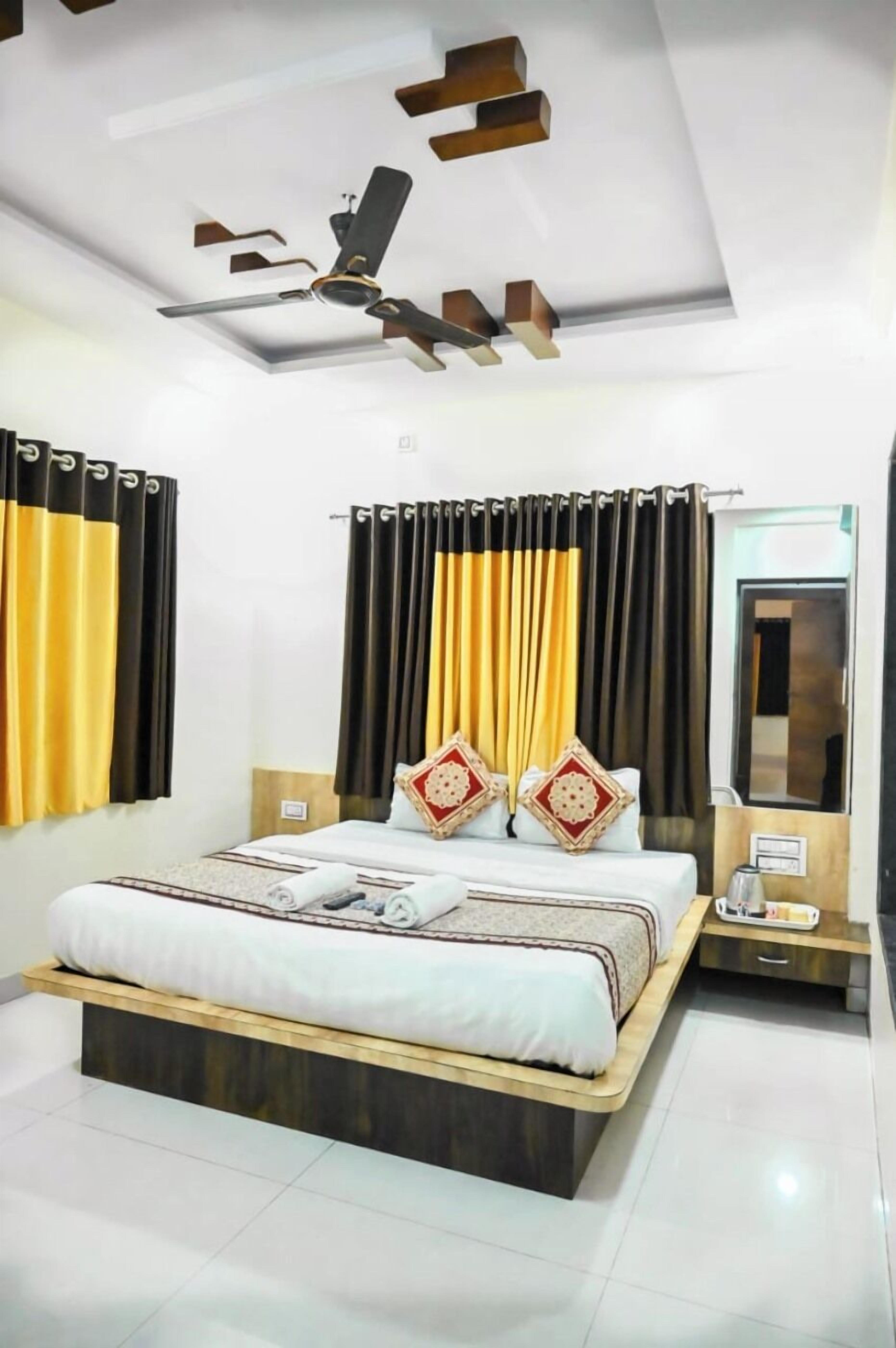 A modern hotel room with a large bed, a ceiling fan, and a bedside table.