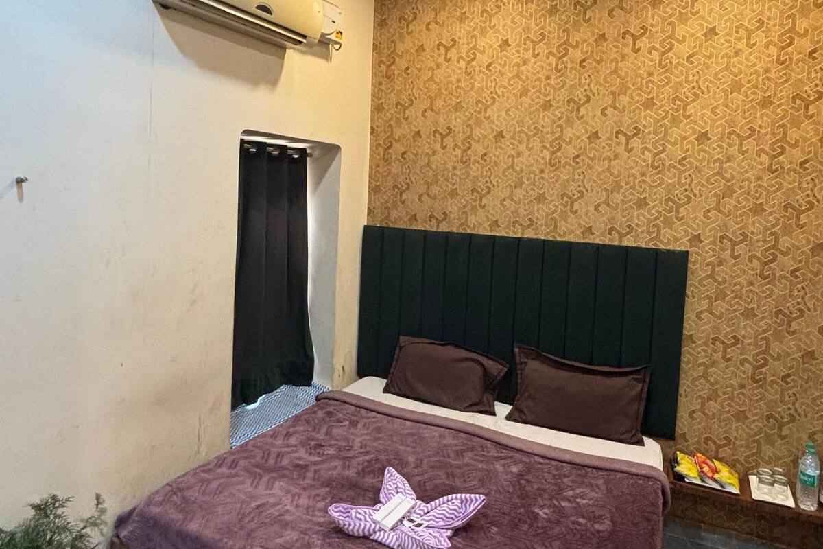 Un dormitorio con una cama, ventilador de techo, equipo de aire acondicionado, pared con diseño y alfombra roja.