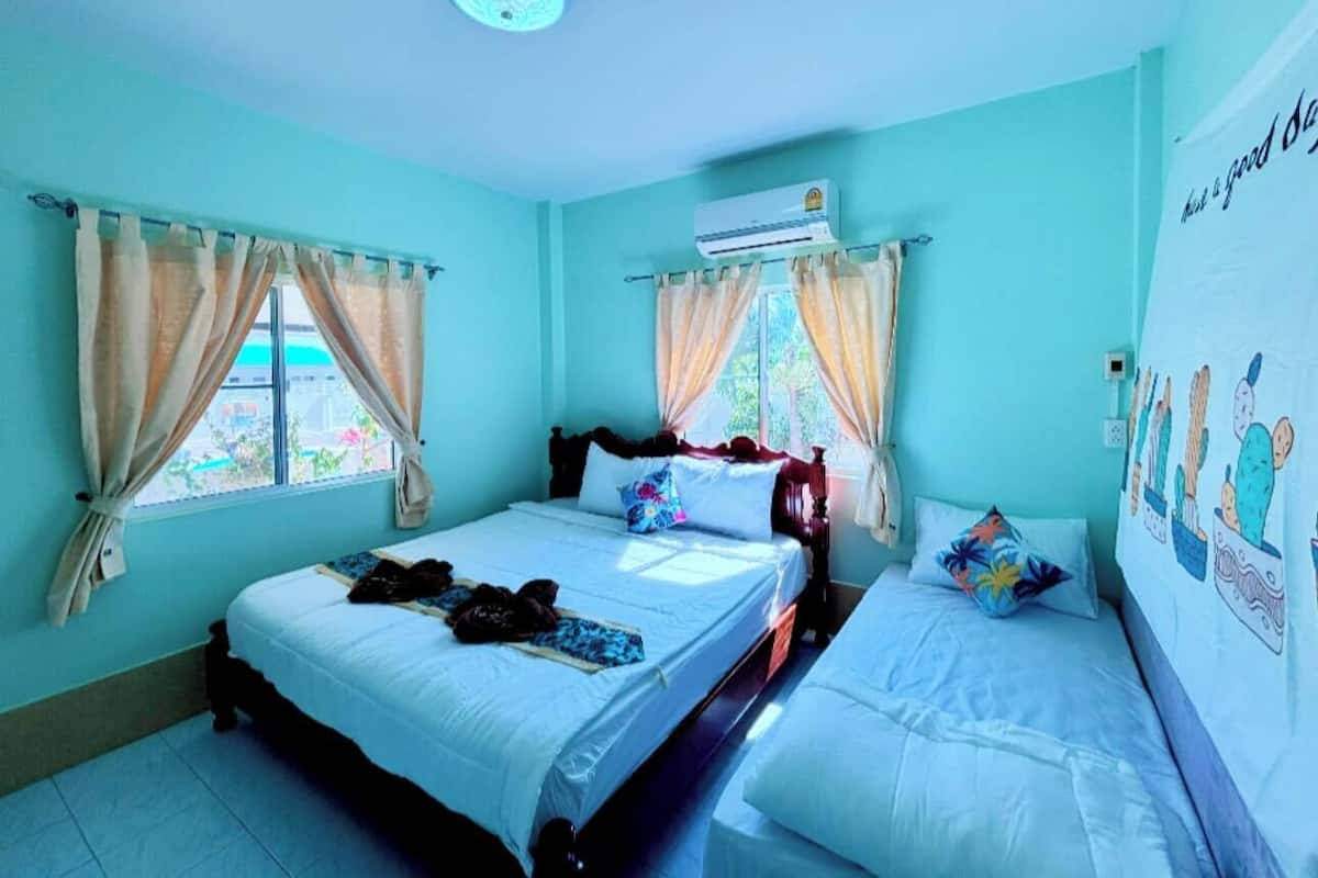 Une chambre avec deux lits, un appareil de climatisation et une fenêtre avec des rideaux.