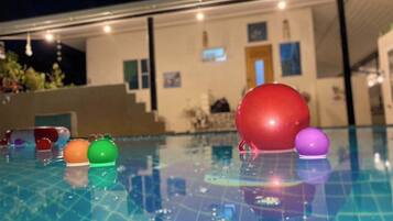 Una piscina con suelo de baldosas y un edificio al fondo.