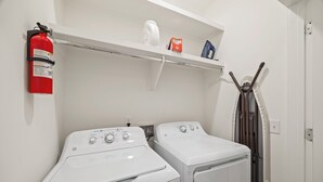 A laundry area with two white washing machines, a fire extinguisher, and a shelf with a kettle and a box. - Luxury 3BR/4BA townhome with 2 Car Garage in Nashville and close to the Airport. (Nashville)