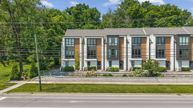 A modern multi-story building with a flat roof, large windows, and a mix of brick and wood paneling. - Luxury 3BR/4BA townhome with 2 Car Garage in Nashville and close to the Airport. (Nashville)