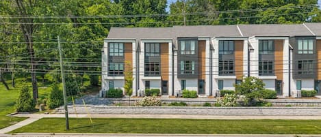 A modern multi-story building with a flat roof, large windows, and a mix of brick and wood paneling.