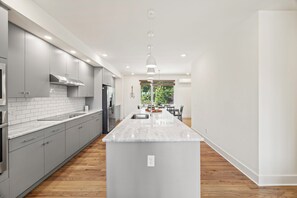 A modern kitchen with grey cabinetry, a marble countertop, and a central island.