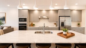 A modern kitchen with a central island, stainless steel appliances, pendant lighting, and a minimalist design. - Luxury 3BR/4BA townhome with 2 Car Garage in Nashville and close to the Airport. (Nashville)