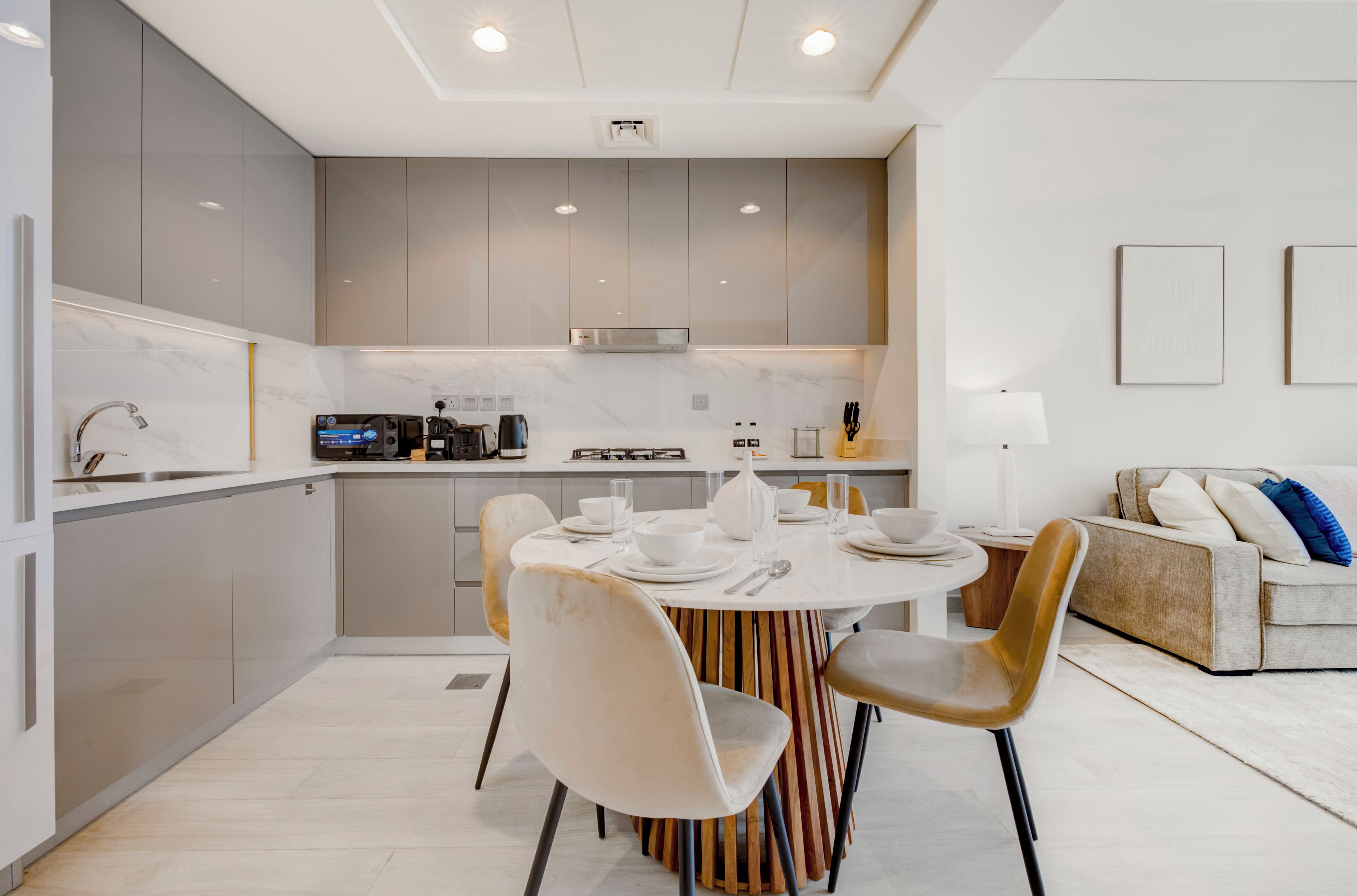 Una cocina moderna con armarios grises, una mesa redonda para comer y un sofá en la sala.