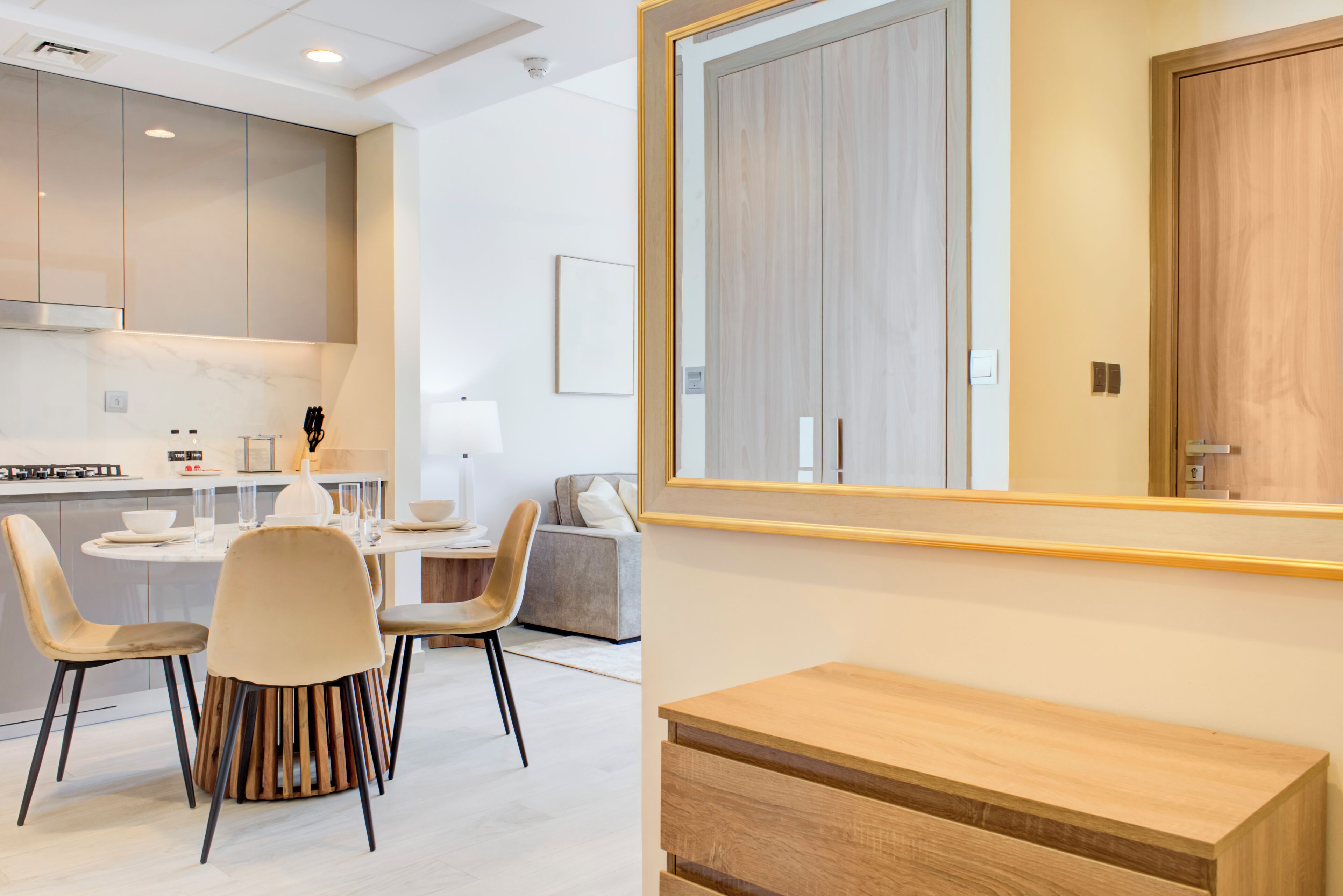 Une cuisine moderne avec un coin repas, des meubles en bois et un grand miroir.