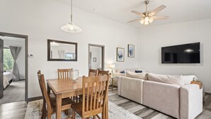 A modern living room with a wooden dining table, beige sofa, and a ceiling fan. - Modern Condo with Sopris Views in Downtown Carbondale (Carbondale)