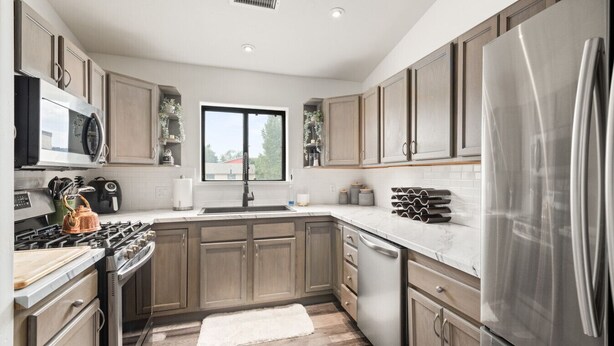 A modern kitchen with wooden cabinets, stainless steel appliances, a large window, and a white rug. - Modern Condo with Sopris Views in Downtown Carbondale (Carbondale)