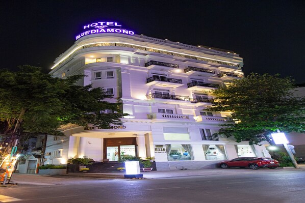 Ein mehrstöckiges Hotel mit einer auffälligen Neonreklame mit der Aufschrift "HOTEL BLUE DIAMOND".