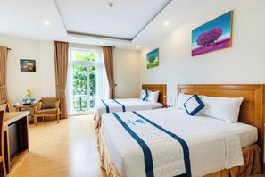 Ein Hotelzimmer mit zwei Betten, einem Schreibtisch, einem Stuhl und einem Balkon mit Vorhängen.