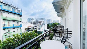 A balcony with a round table and chairs, overlooking a cityscape with multi-story buildings. - Blue Diamond Airport Hotel (Ho Chi Minh City)