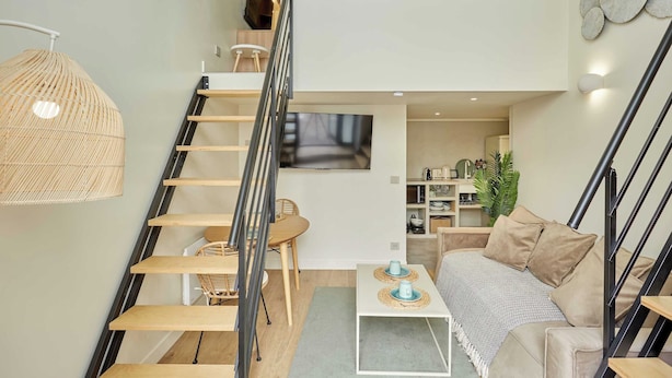 Un intérieur moderne comprenant un escalier, un canapé, une table basse et un coin repas.