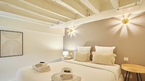 Une chambre à coucher avec un grand lit, deux oreillers, une table de chevet et une lampe fixée au mur.