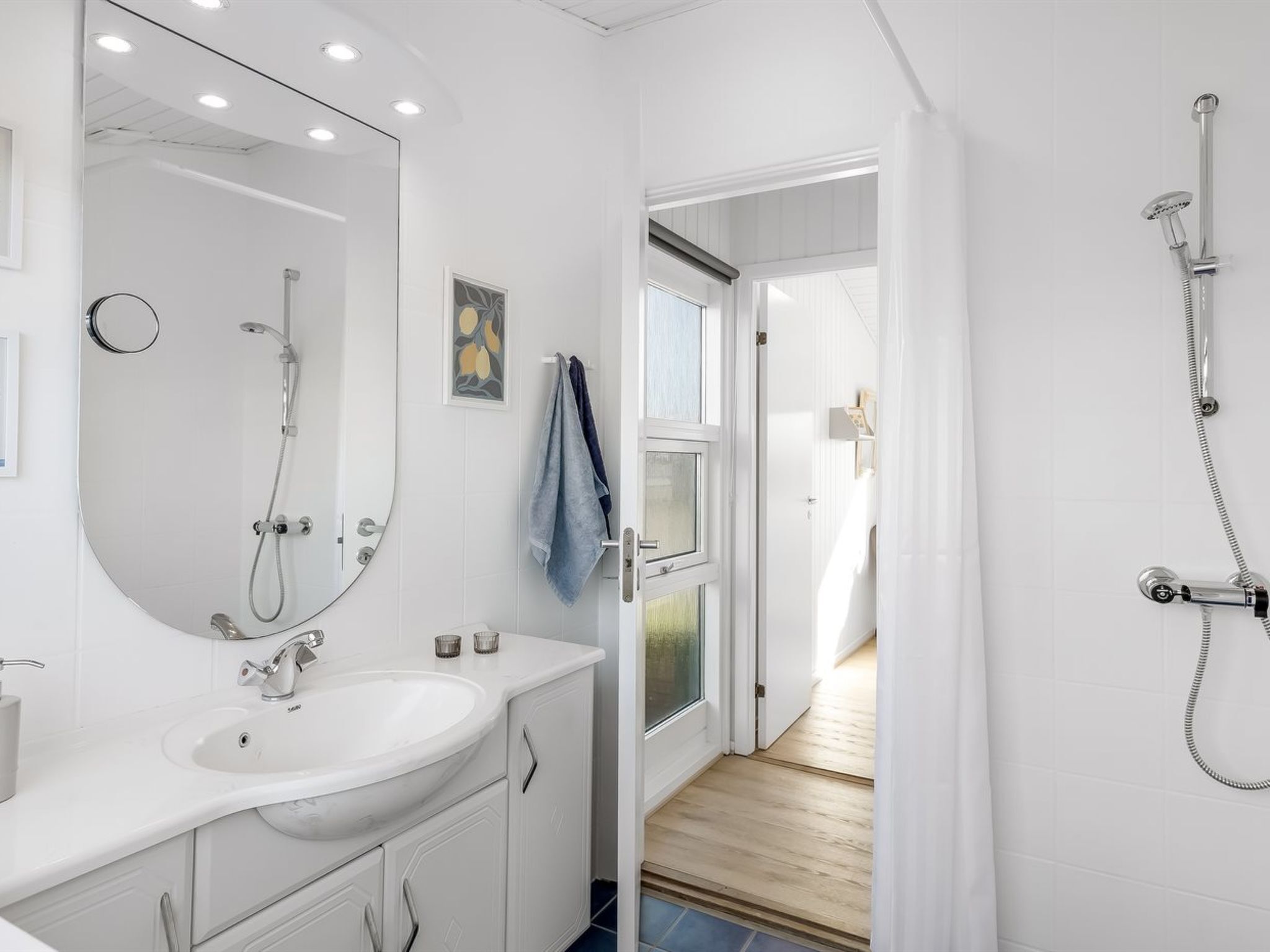 Une salle de bain moderne avec un lavabo blanc, un miroir et une douche.